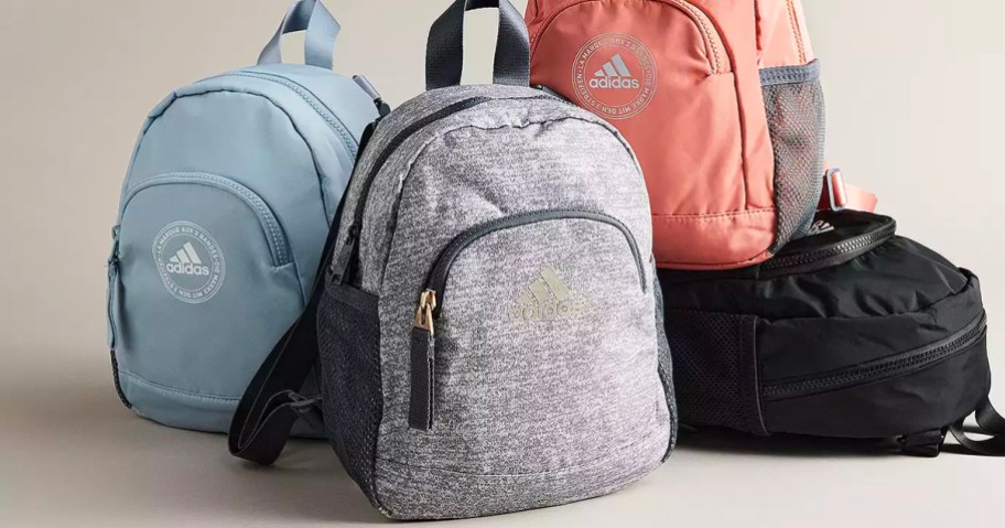 blue, gray, peach and black adidas backpacks in a pile