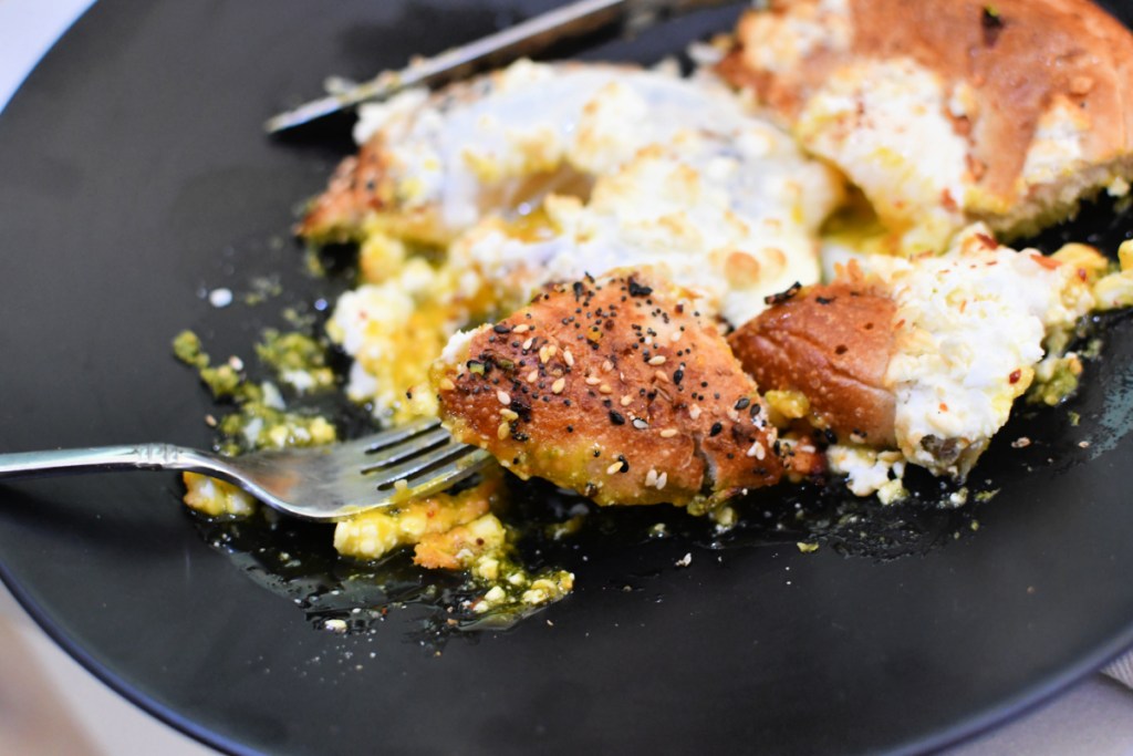 bite of air fryer bagel with eggs and pesto