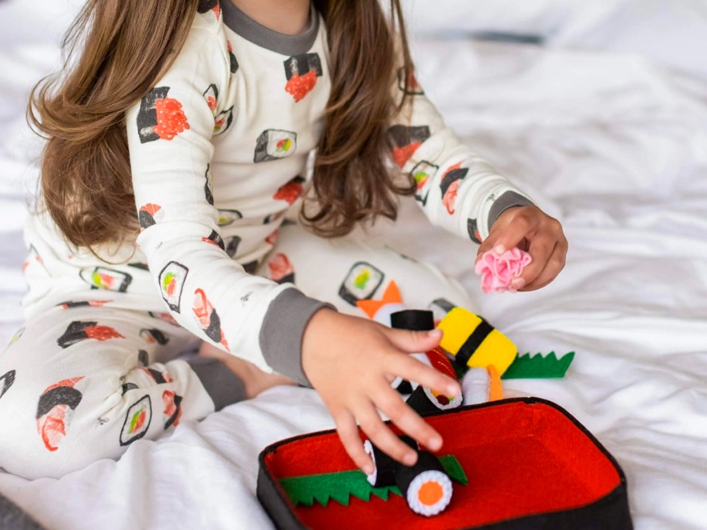 girl wearing sushi pajamas with sushi toys