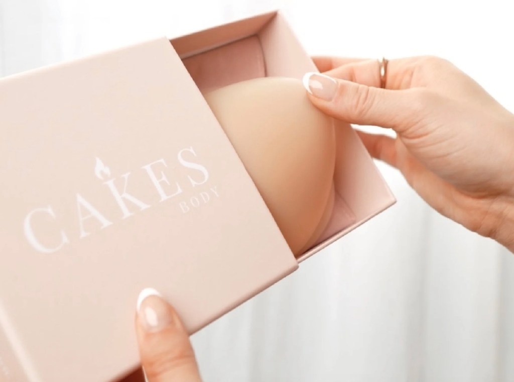 hand holding light pink cakes box with nipple covers inside