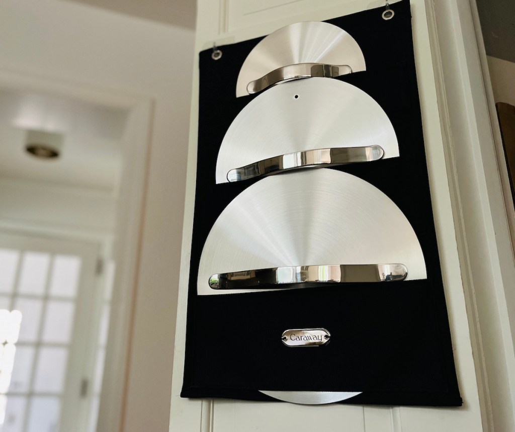 caraway stainless steel lids hanging in organizer on door