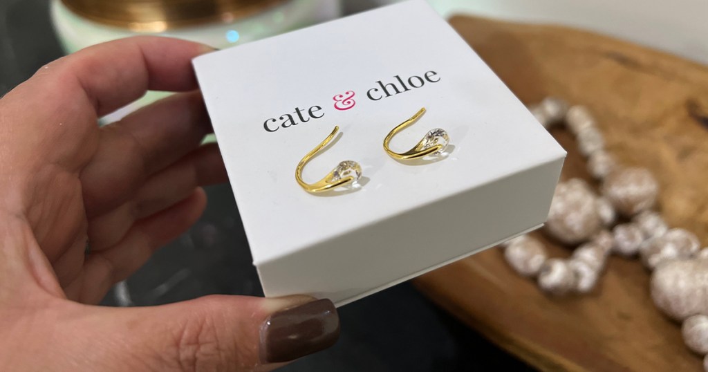 hand holding box with gold earrings on top