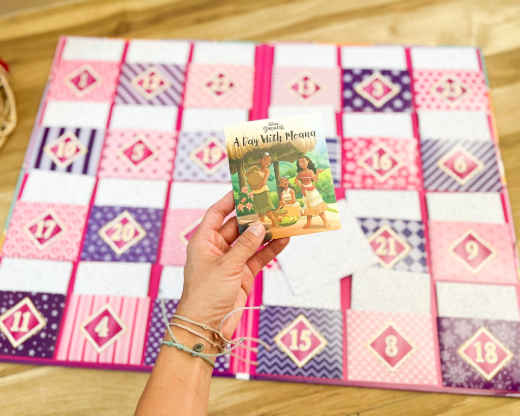 hand holding mini books over advent calendar