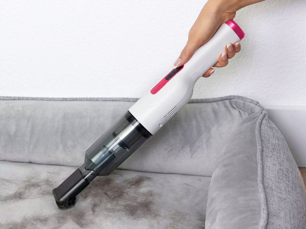 using white and pink handheld vacuum on pet bed