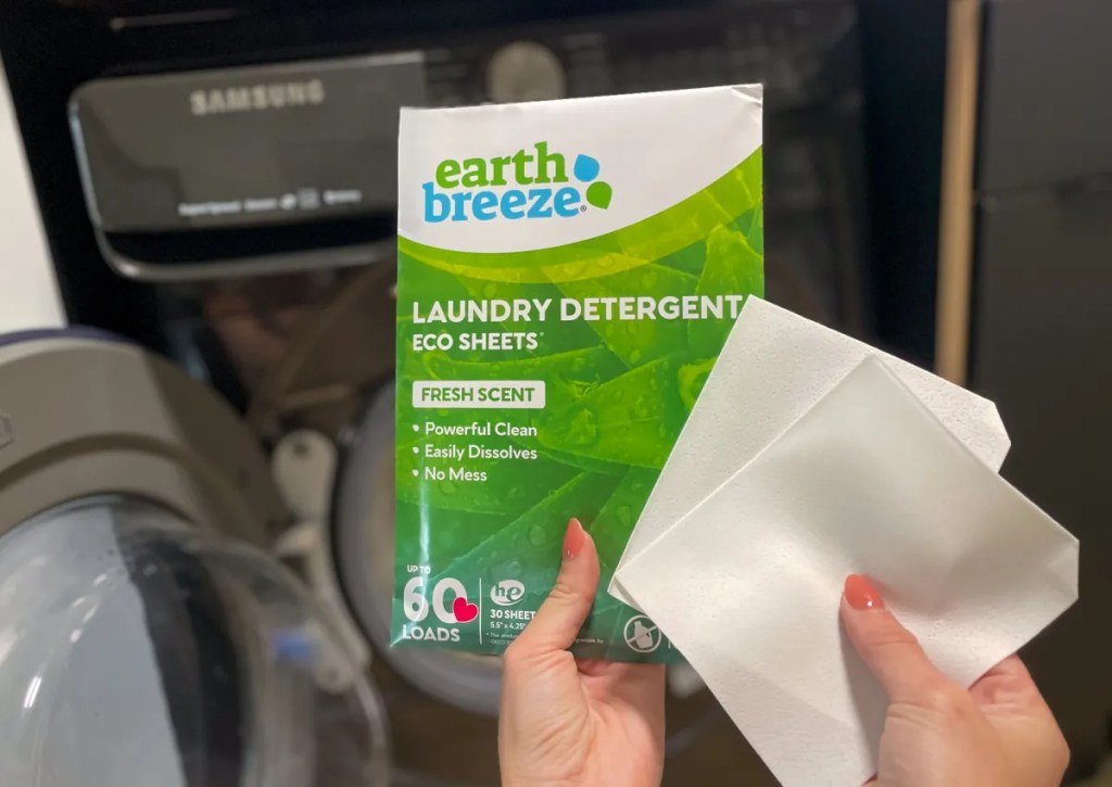hand holding sheet and packaging of earth breeze laundry detergent