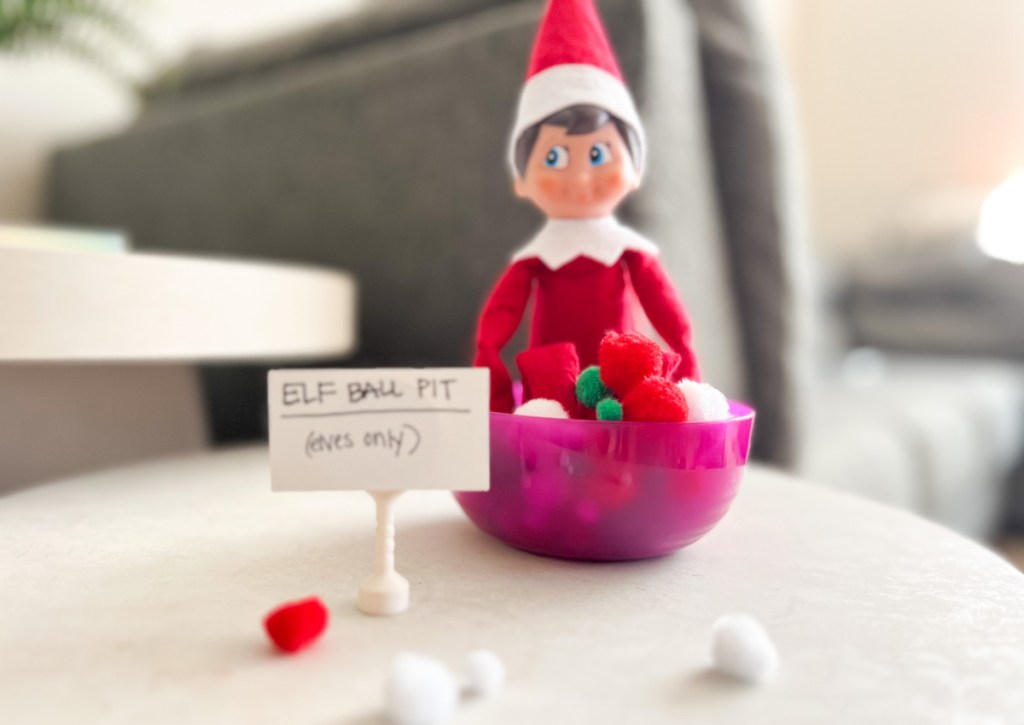 elf sitting in a bowl of pom poms