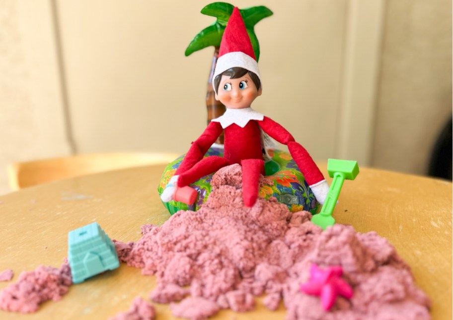 elf sitting in pink sand