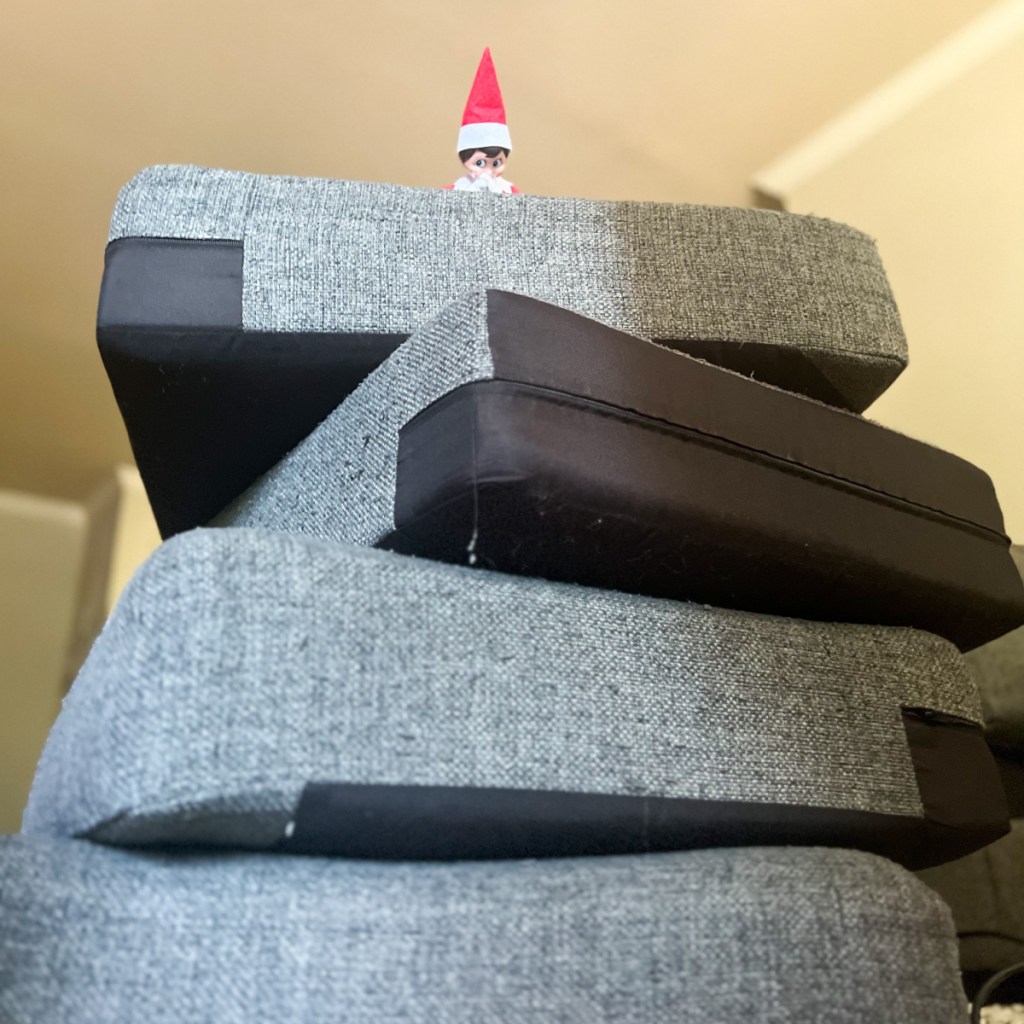 elf at the top of a pile of couch cushions