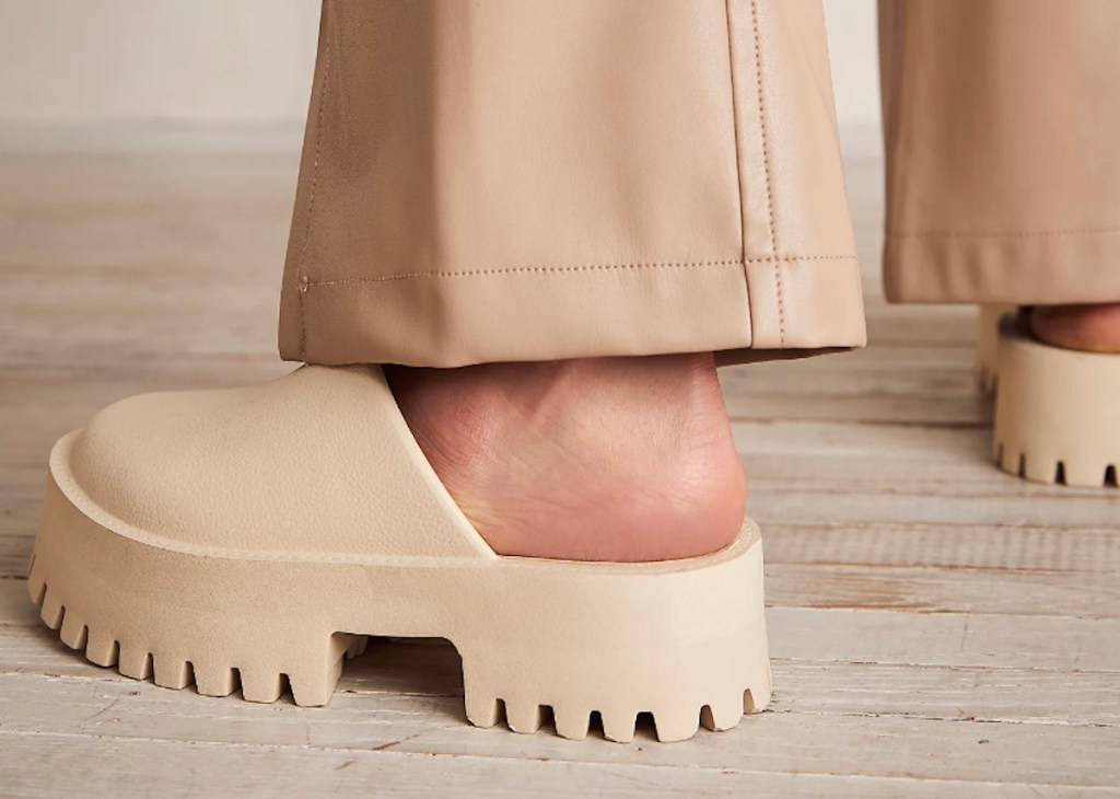 close up of foot wearing beige tan colored chunky platform shoes