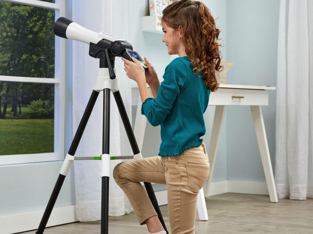 girl playing with telescope and looking out the window