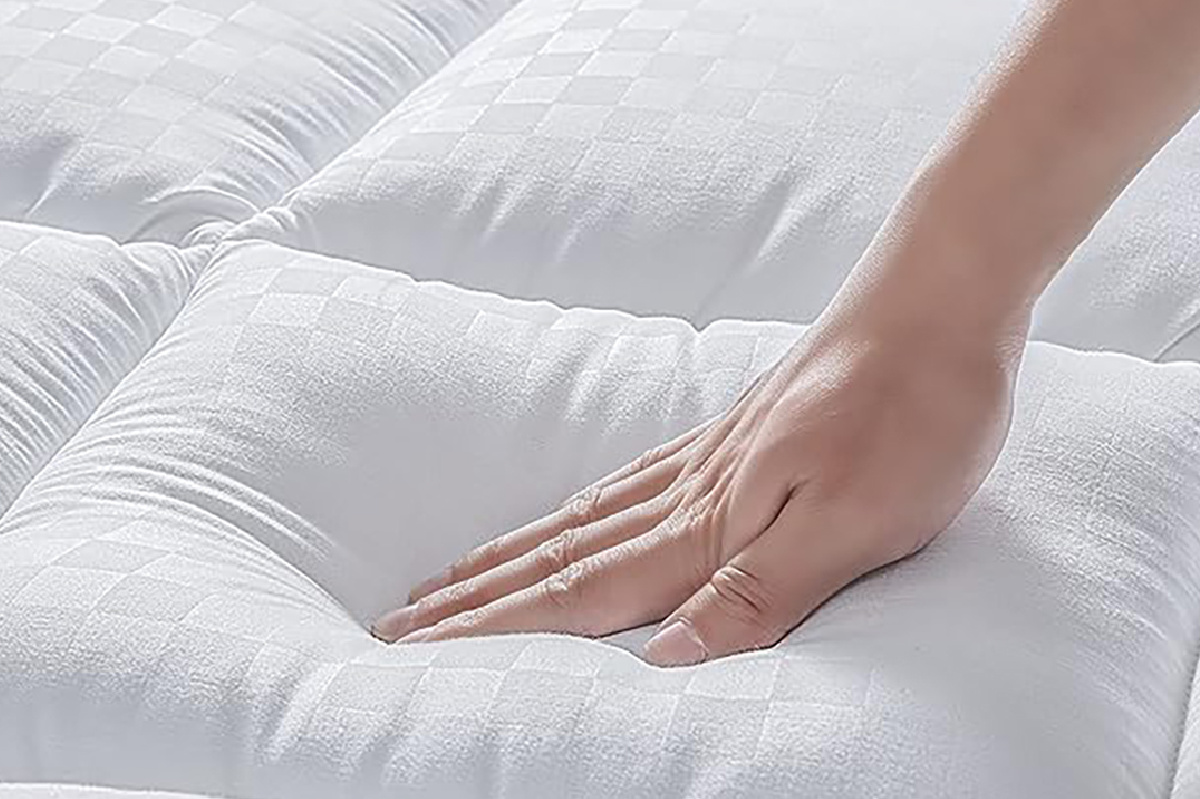 hand touching the mattress topper
