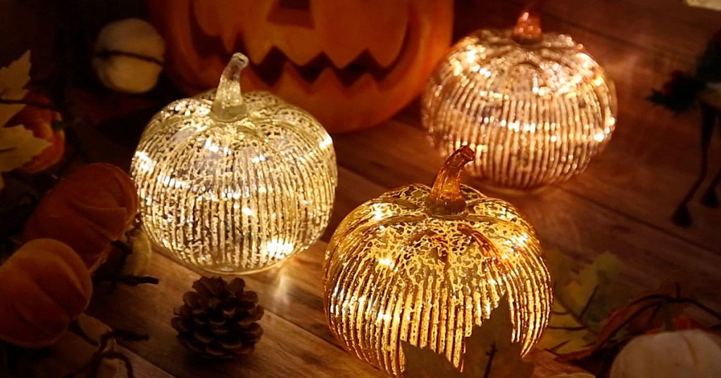 three glass light-up pumpkins on table