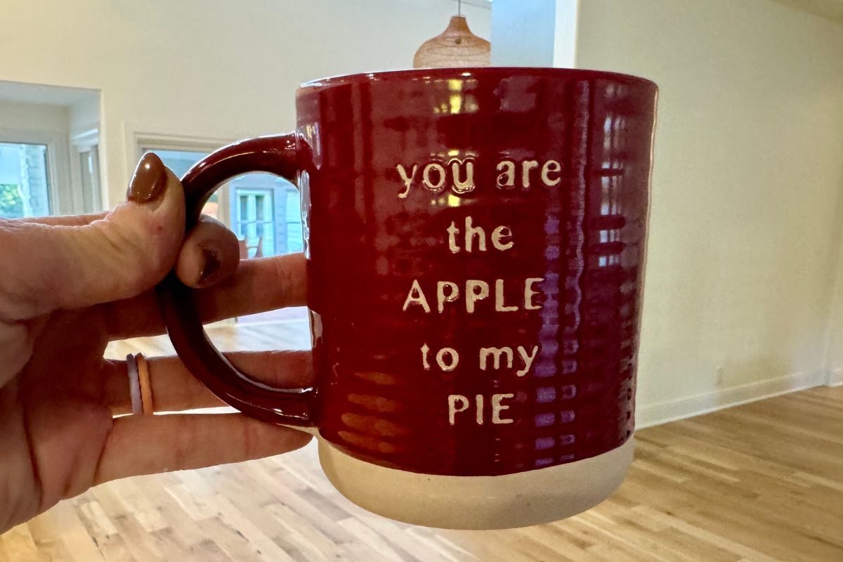 a womans hand holding a coffee mug that says apple to my pie