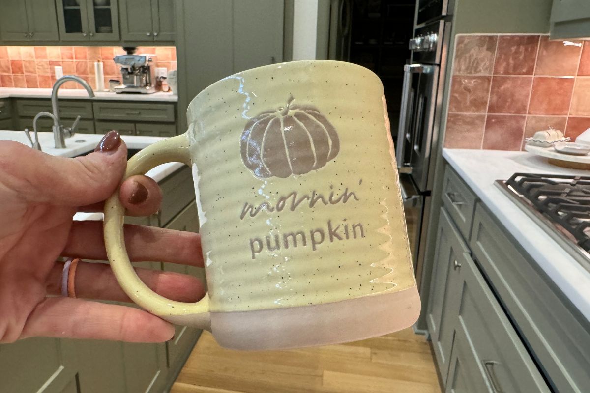 a womans hand holding a coffee mug that says mornin' pumpkin