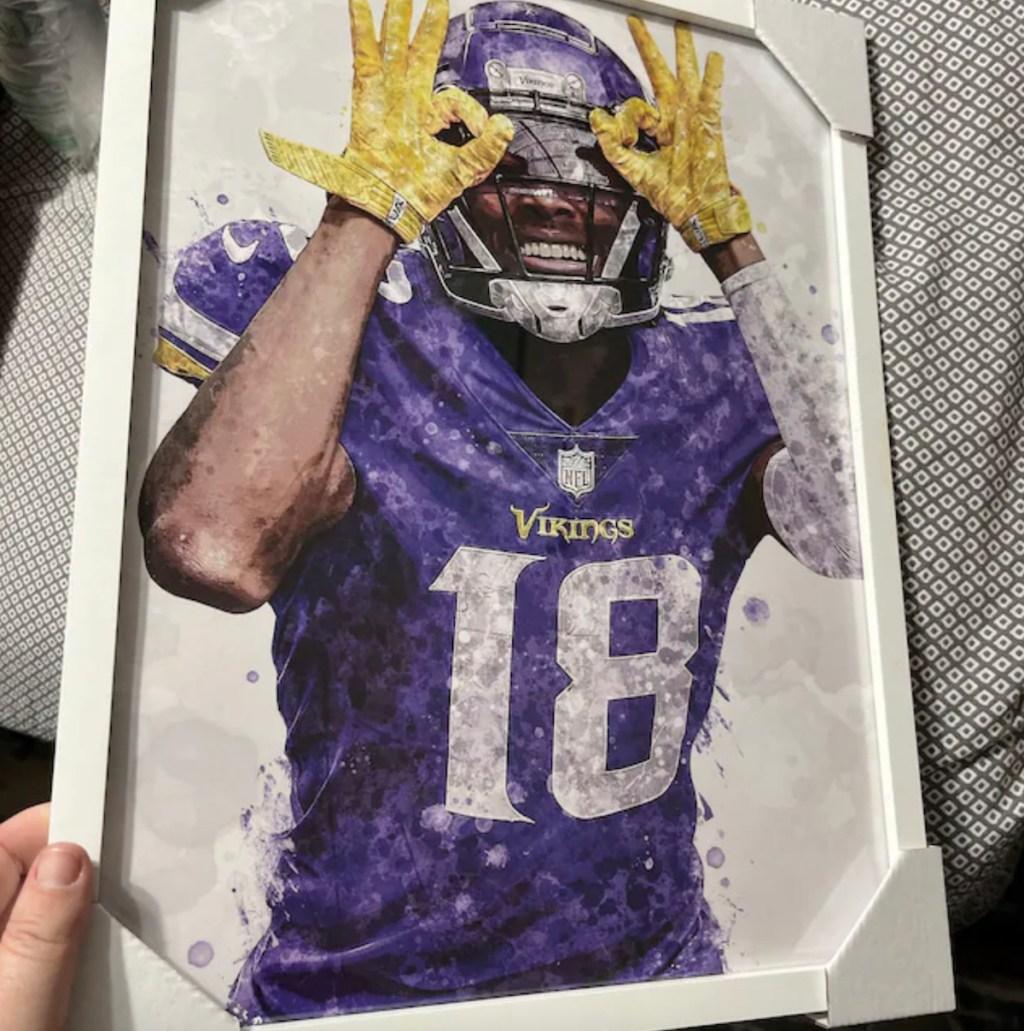 hand holding a framed art piece of justin jefferson number 18 football player