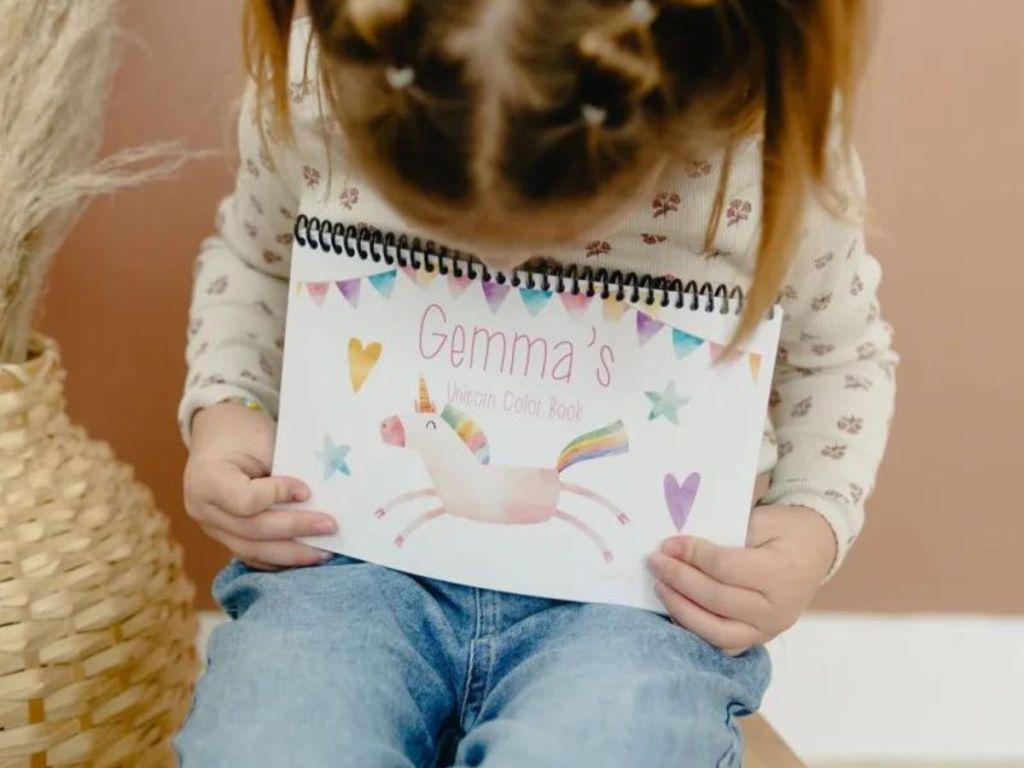 girl holding personalized coloring book on her lap