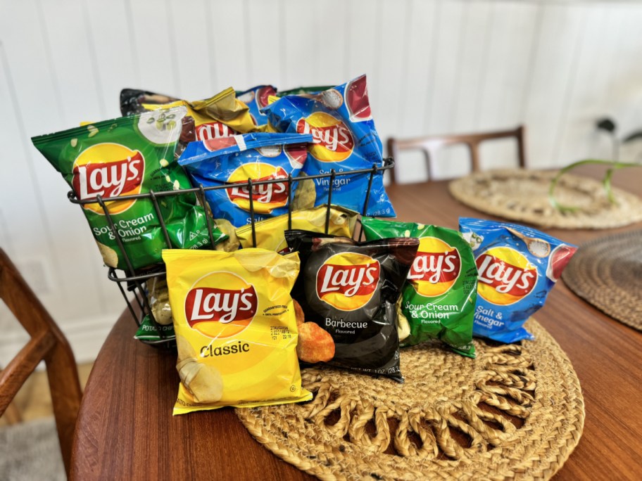 individual bags of various lays potato chips displayed on a table and in a wire basket