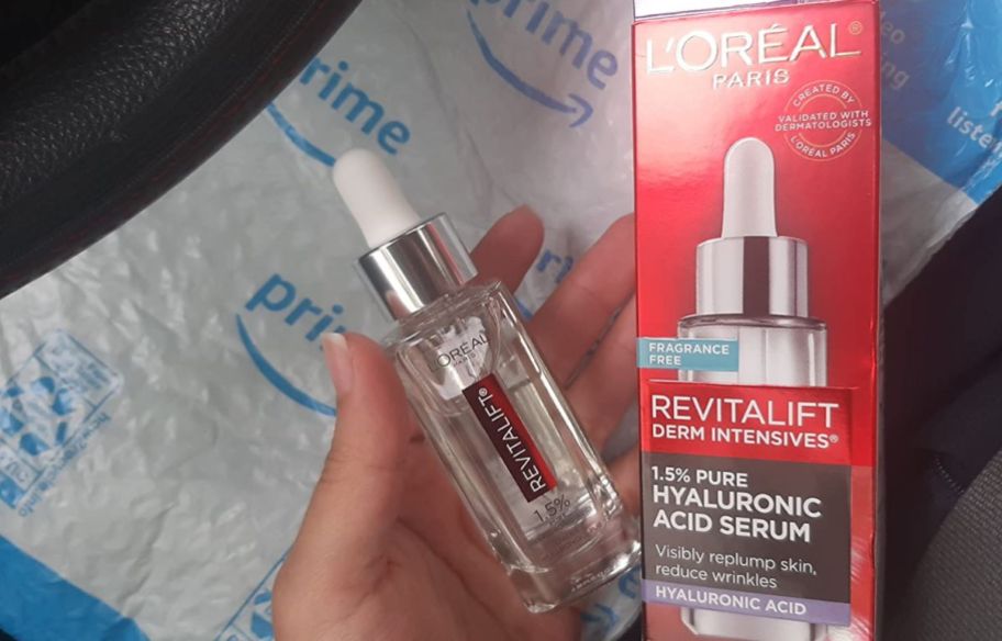 a womans hand holding a bottle of loreal revitalift serum and box