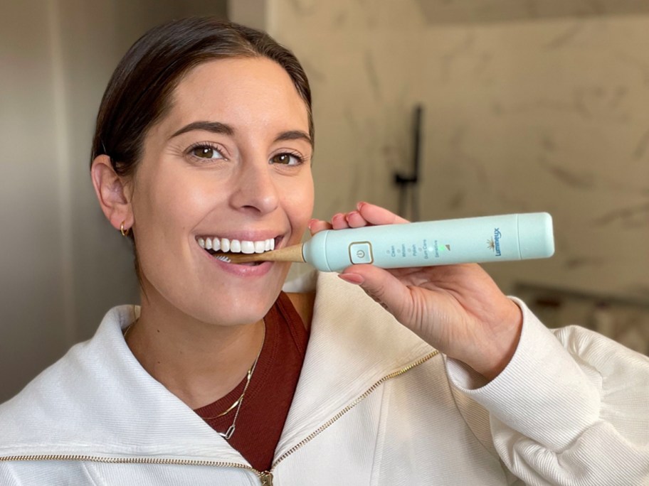 woman brushing teeth with teal lumineux toothbrush 
