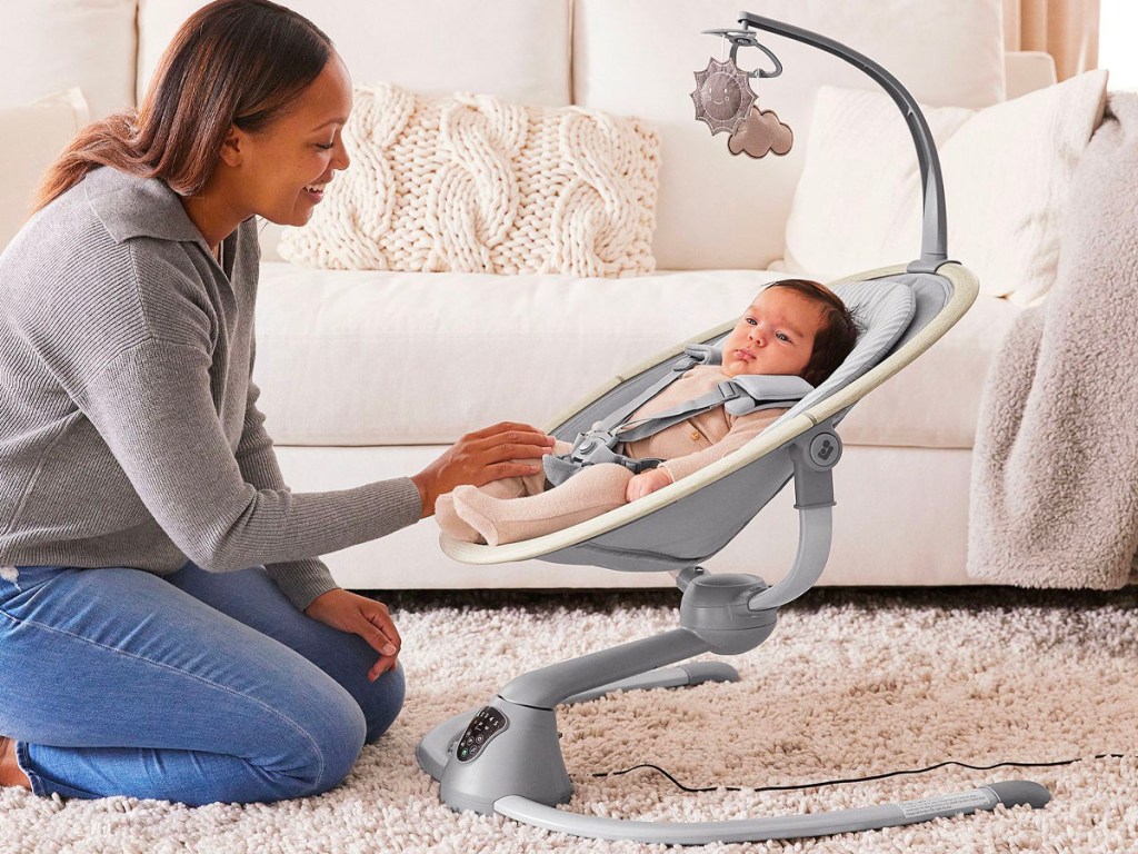 mom sitting with baby in gray swing