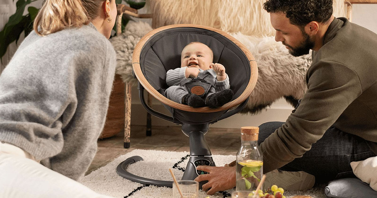 baby in gray swing with parents watching
