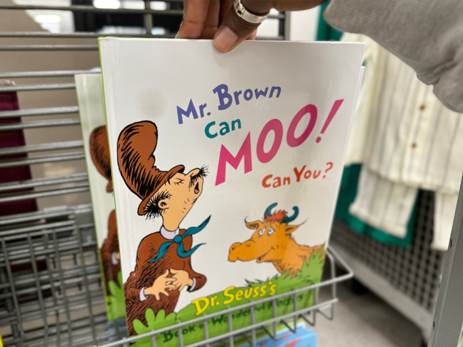 hand reaching for mr brown can moo book on shelf in store 