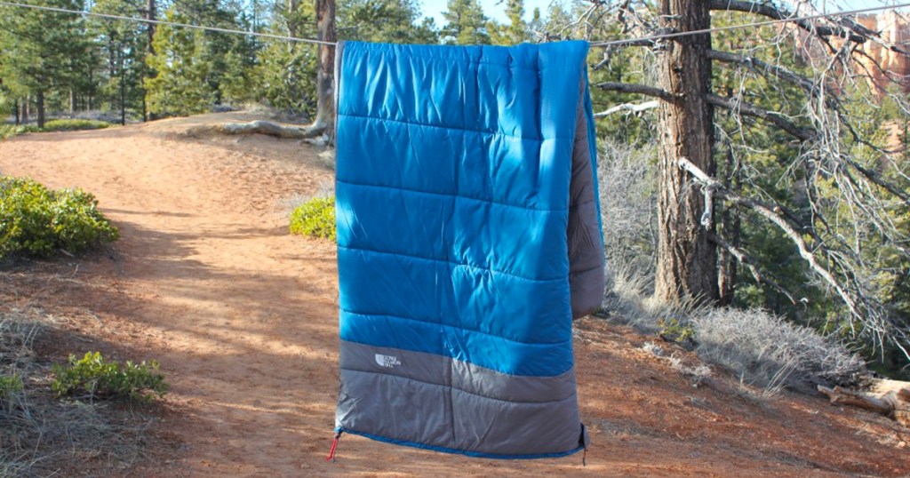 blue north face sleeping bag hanging in forest