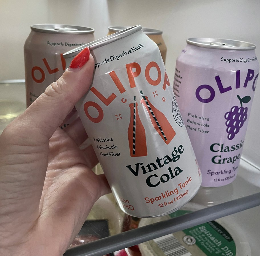 hand pulling olipop cola can out of fridge