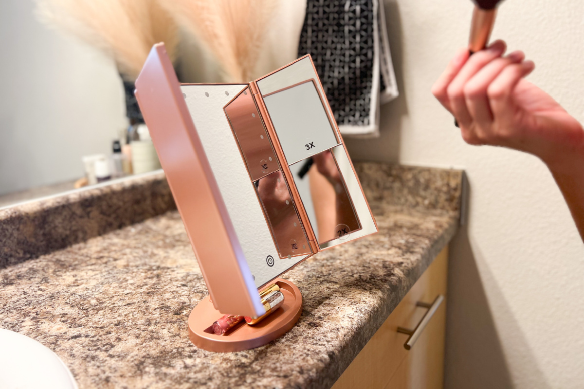 Offener beleuchteter Kosmetikspiegel am Rand einer Badezimmerarbeitsplatte aus Marmor