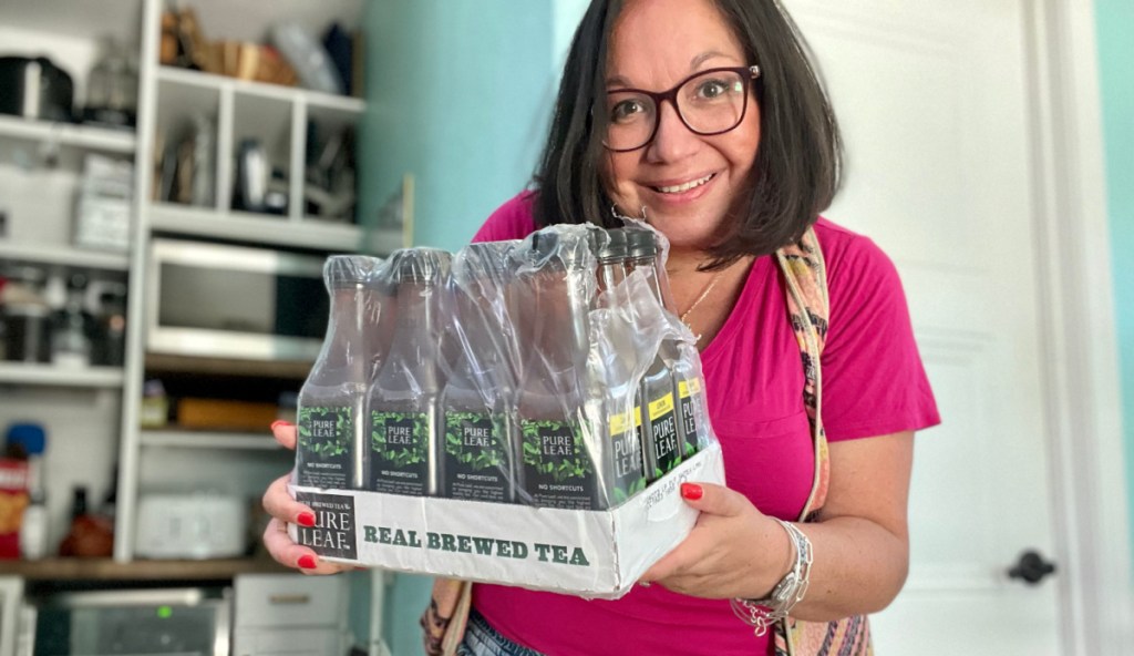 woman holding a shrink wrapped pack of pure leaf iced tea bottles