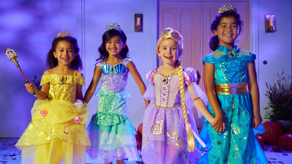 four young girls holding hands and wearing disney princess costumes
