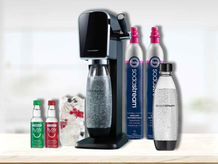 black SodaStream Art machine with 2 CO2 containers, 2 plastic bottles, glass of soda, and 2 blubly flavors
