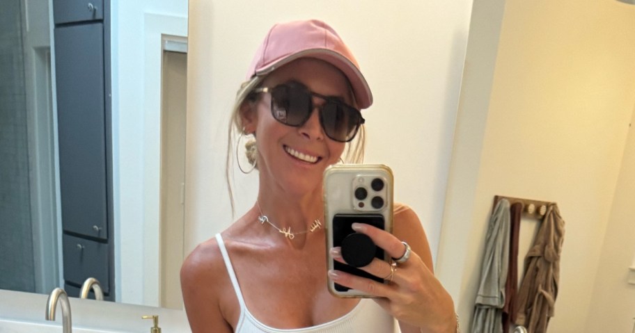 woman in hat and sunglasses taking selfie