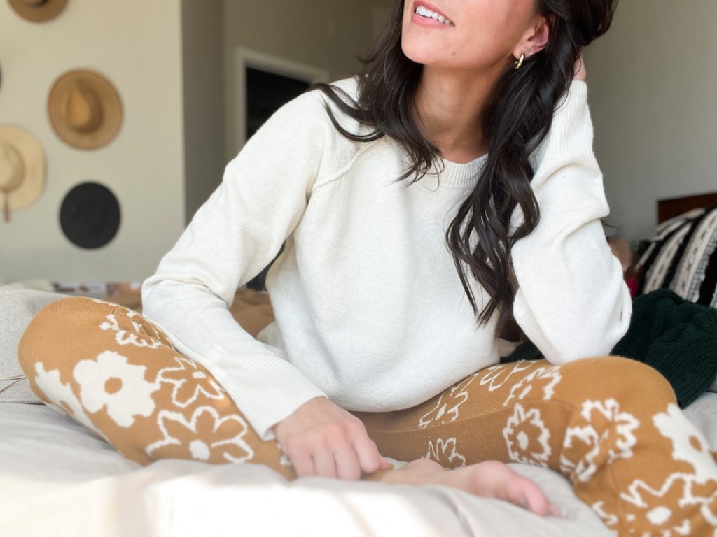 woman in white sweater sitting on bed