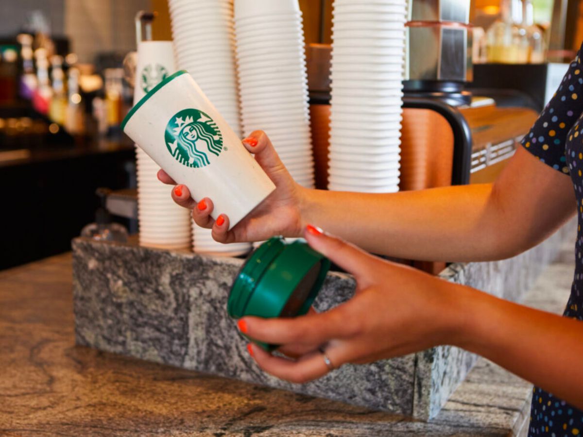a womans hands holding a reusable cup at a starbuck store 
