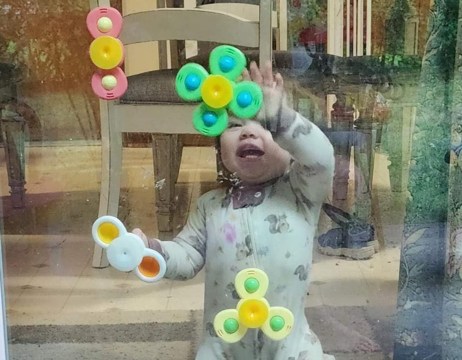 baby playing with suction cup spinner toys on window