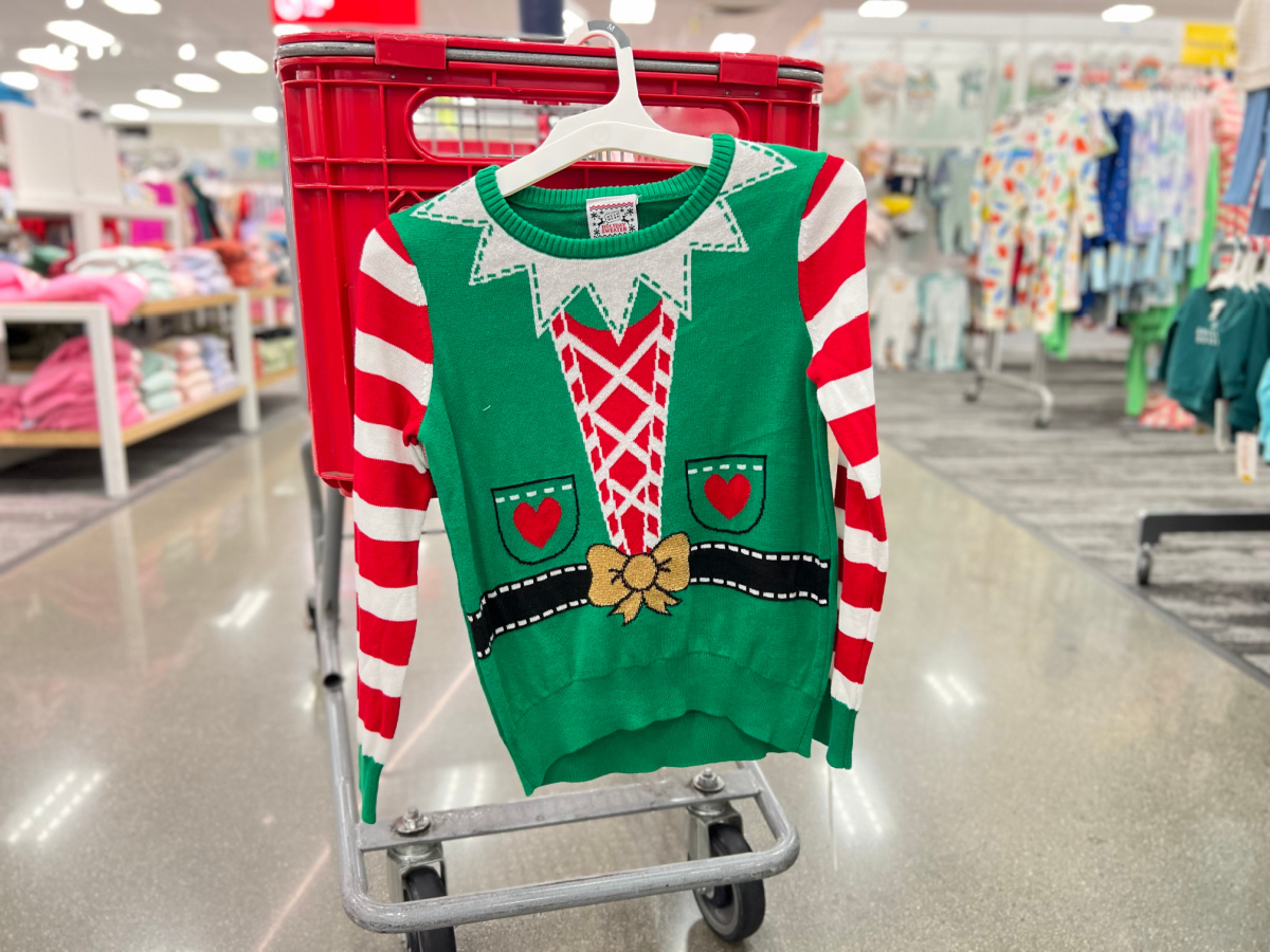girls elf holiday sweater hanging off the back of a target shopping cart in store
