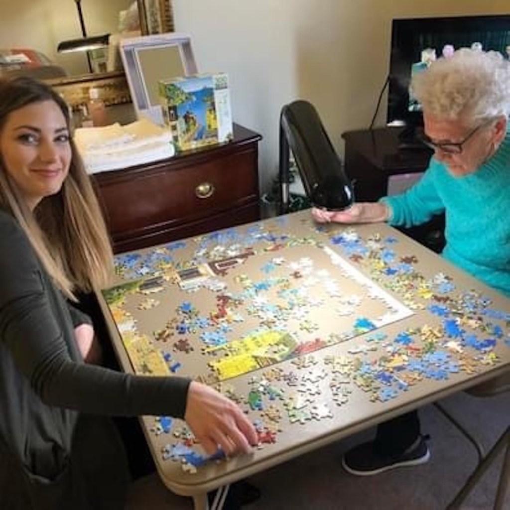 young woman and grandma doing a puzzle on card table