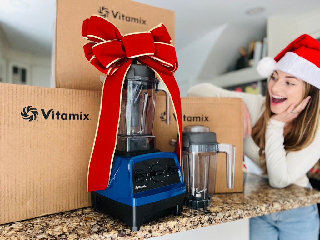 Blue vitamix blender sitting on countertop with big brown boxes and big red bow