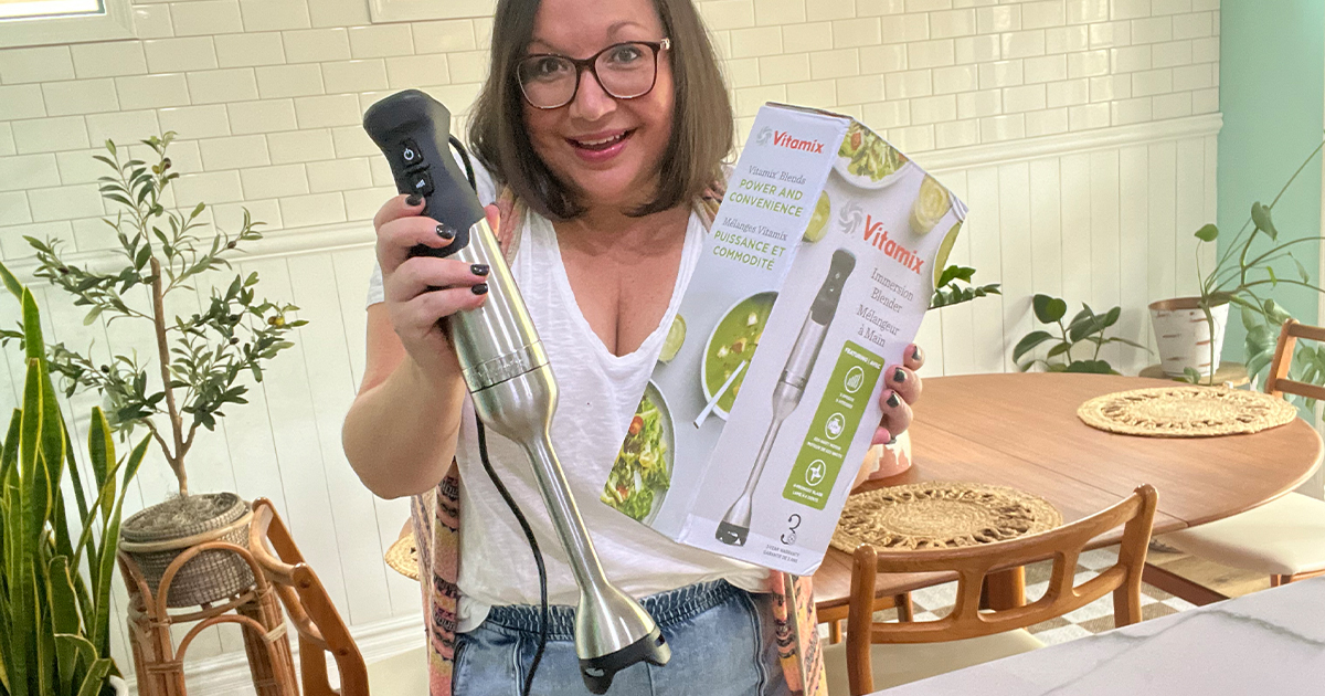 woman holding immersion blender and box in kitchen