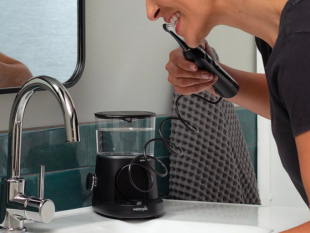 woman using black waterpik over sink