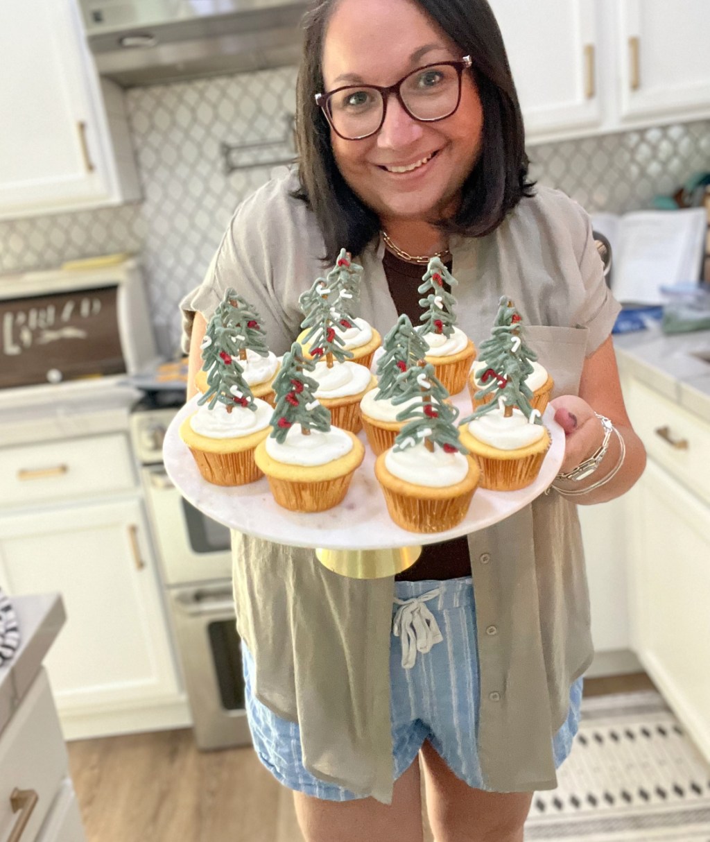 woman holding a cake stand with christmas tree cupcakes