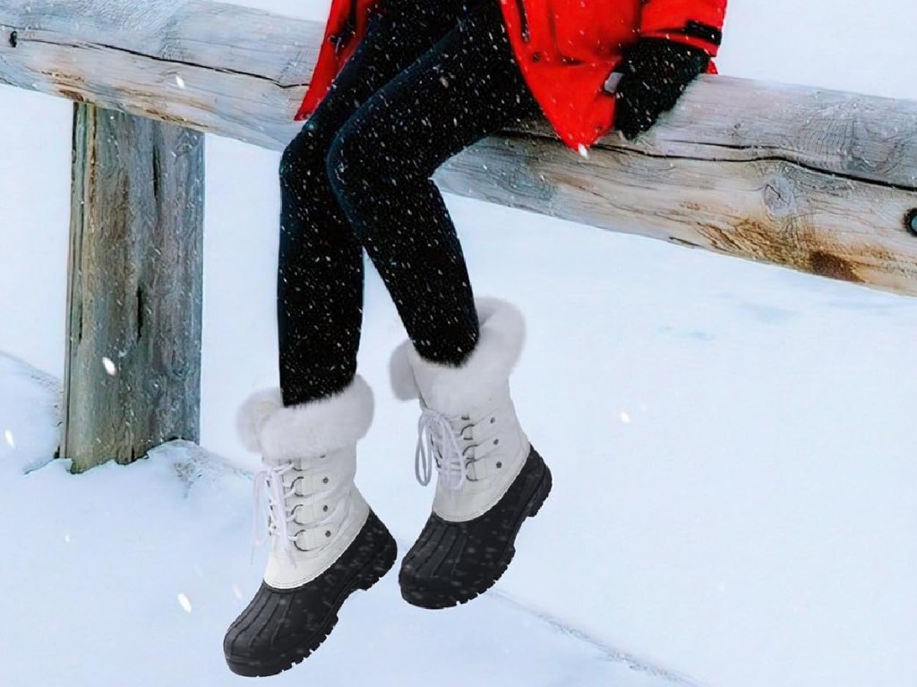 woman sitting down wearing white and black snow boots