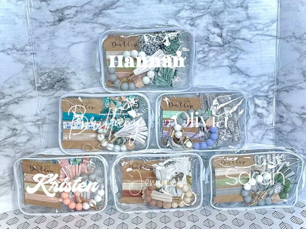 several clear cosmetic bags with custom names on them filled with jewelry and hair accessories