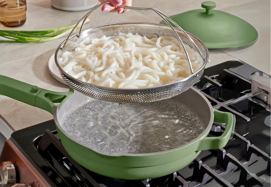 green ceramic Our Place Always Pan 2.0 on stove with steamer basket