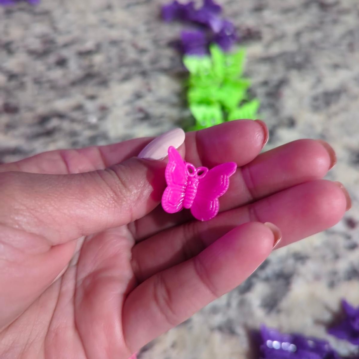 a womans hand holding a hot pink mini butterfly clip