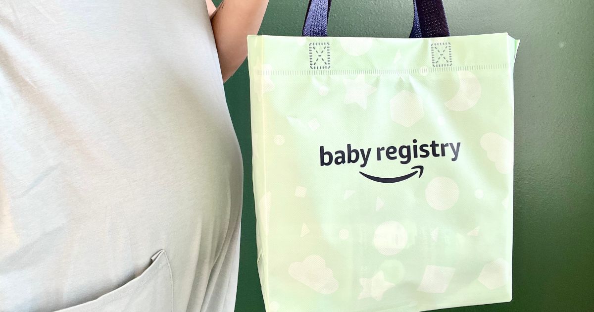 a pregnant woman holding an Amazon baby registry bag