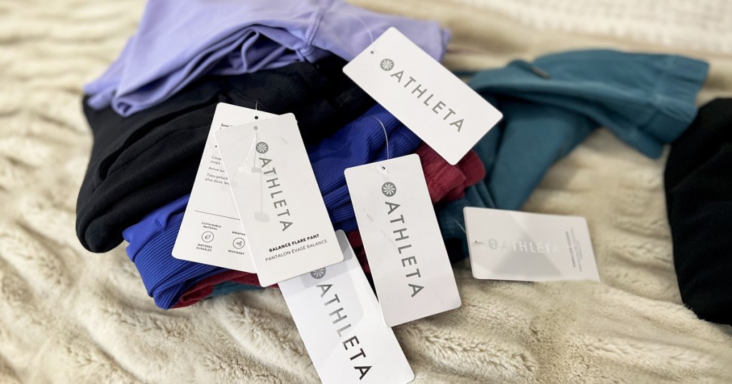 pile of athleta clothing with tags on bed