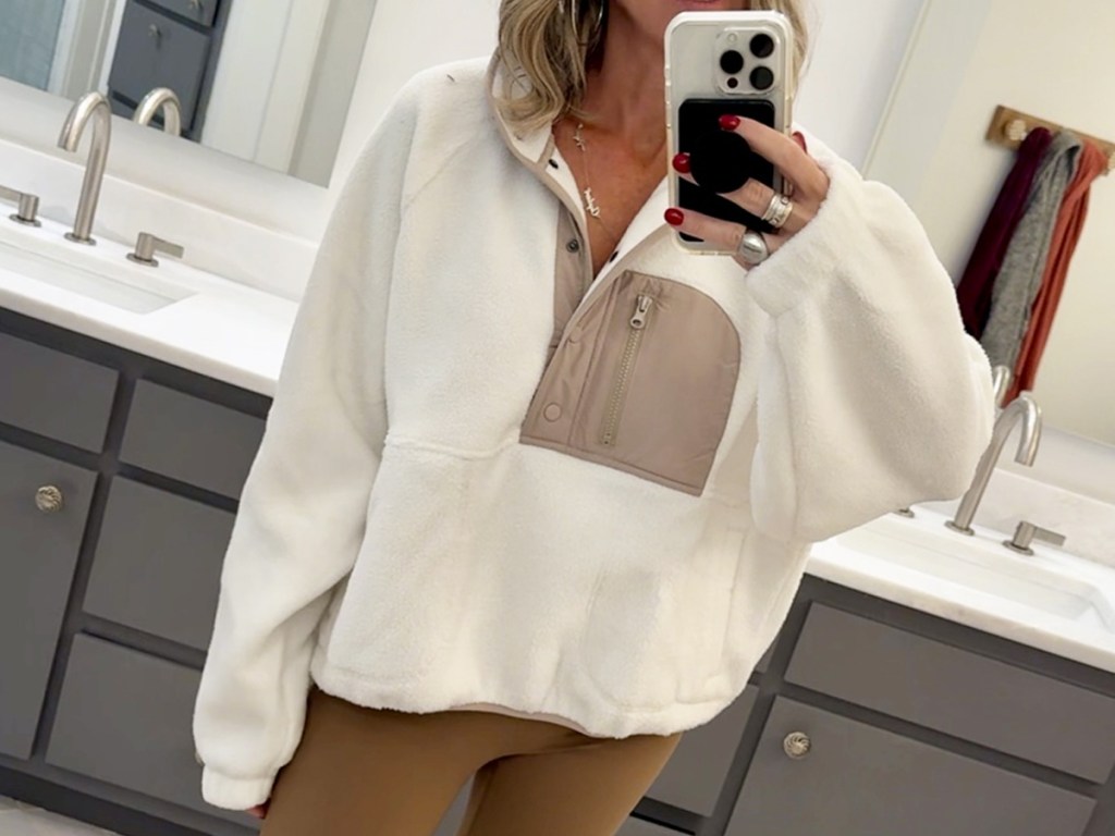 woman wearing white sherpa pullover taking selfie in mirror