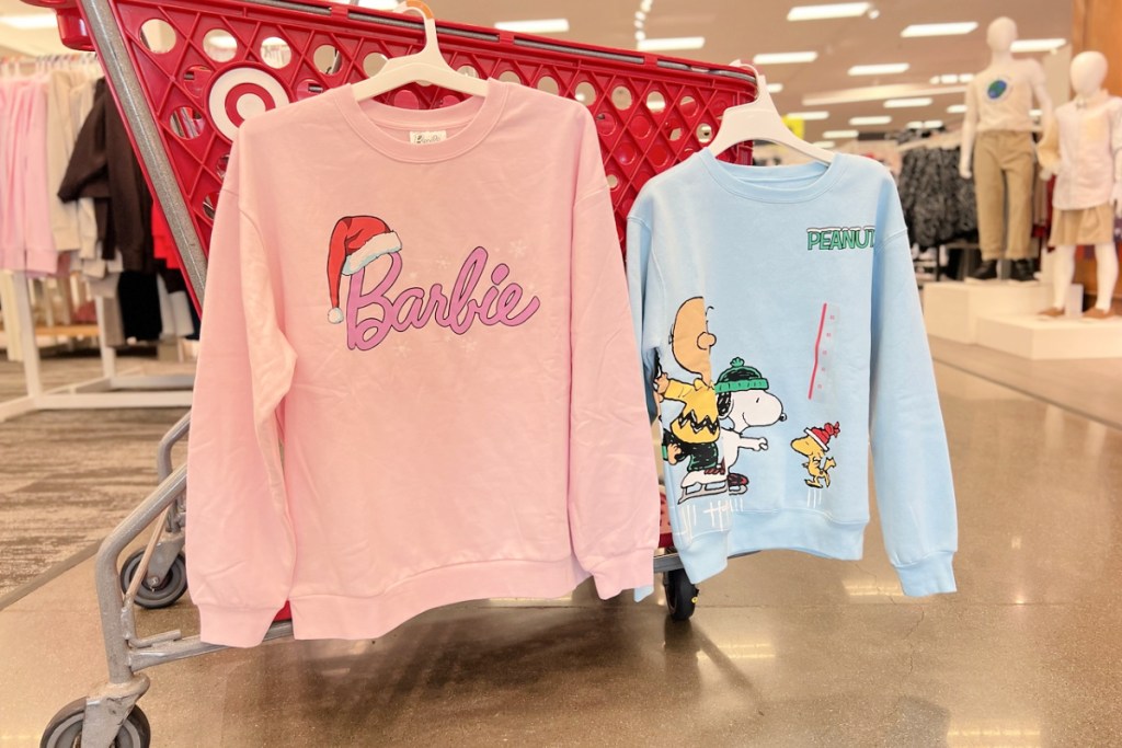 Barbie and Charlie Brown Target Christmas Sweatshirts hanging on a target cart